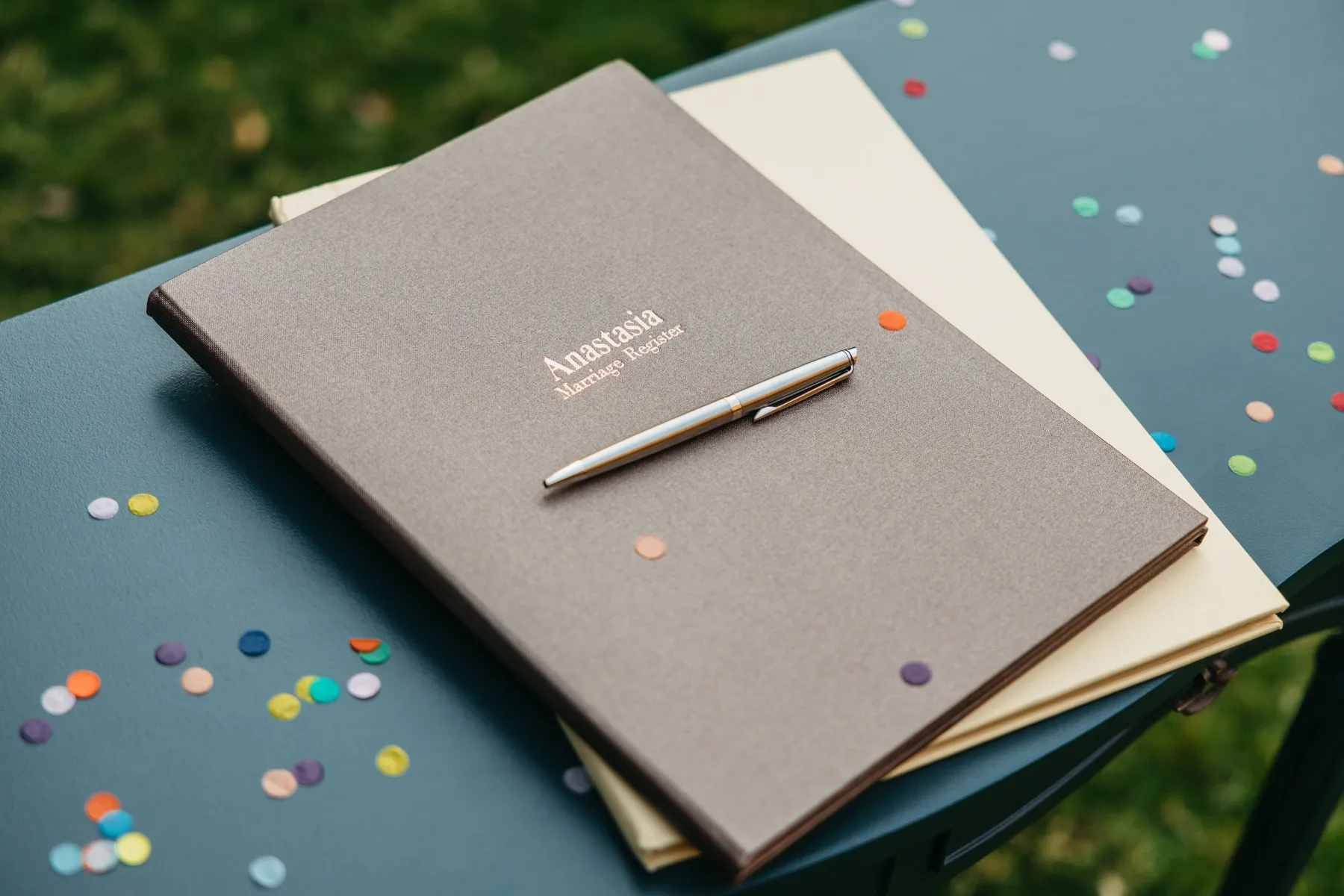 Anastasia's ceremony folder and pen on a signing table with confetti