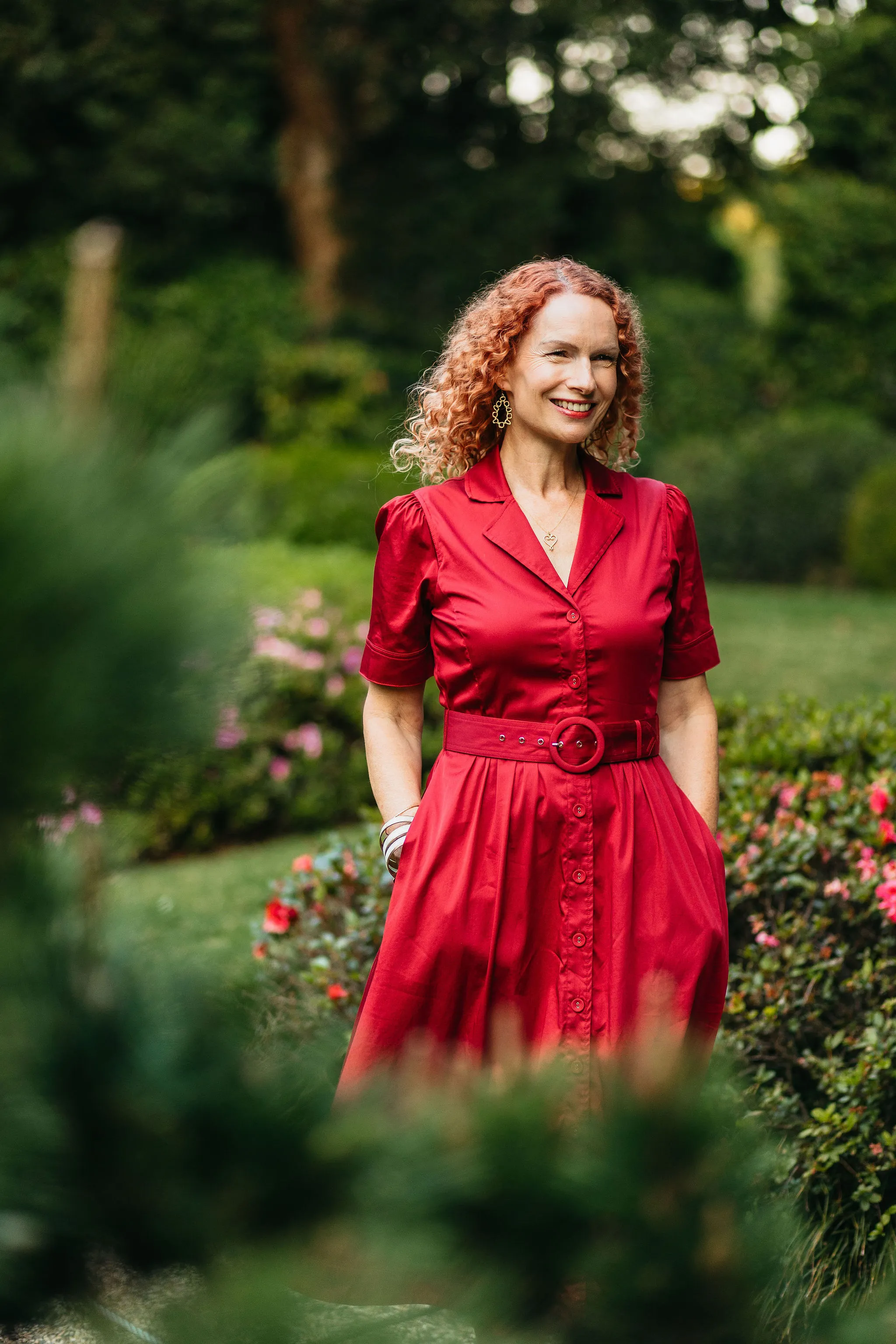Anastasia standing in a red dress in a garden