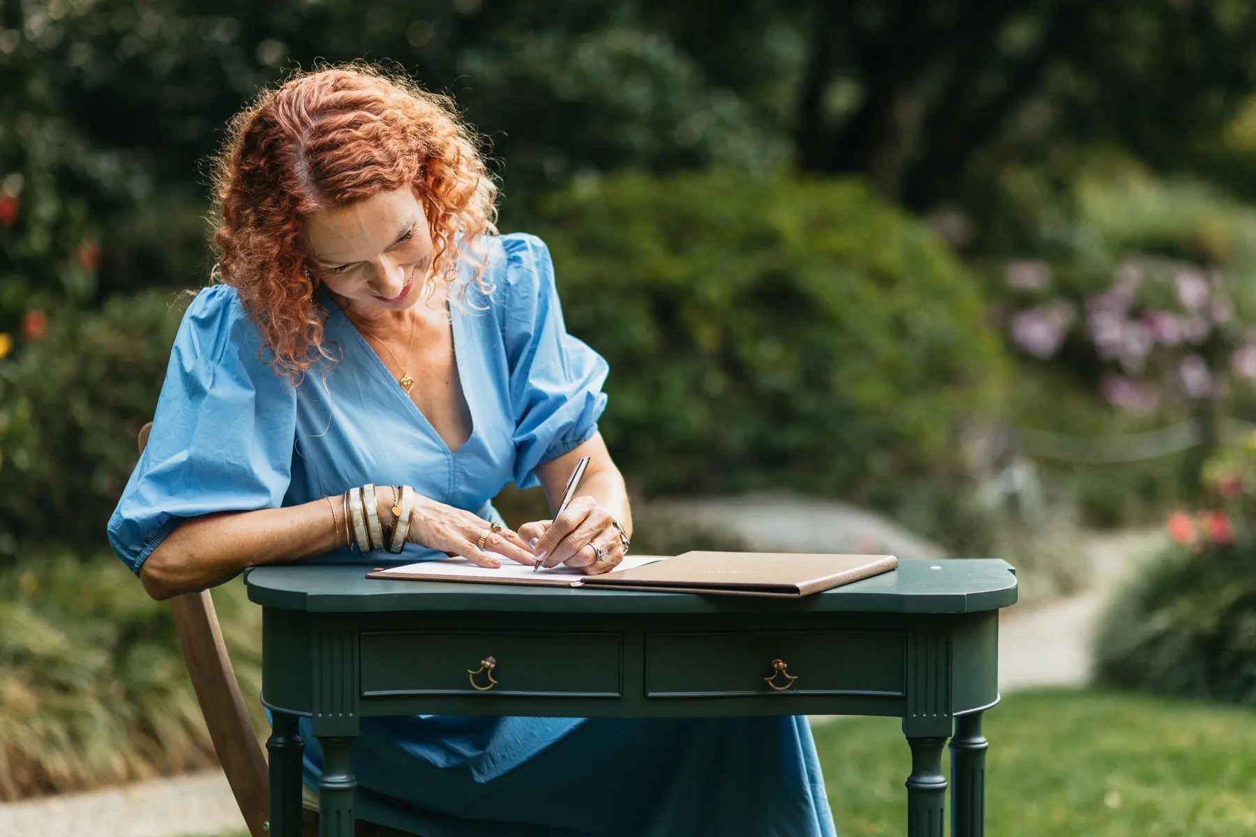Anastasia preparing paperwork at a signing table in a garden